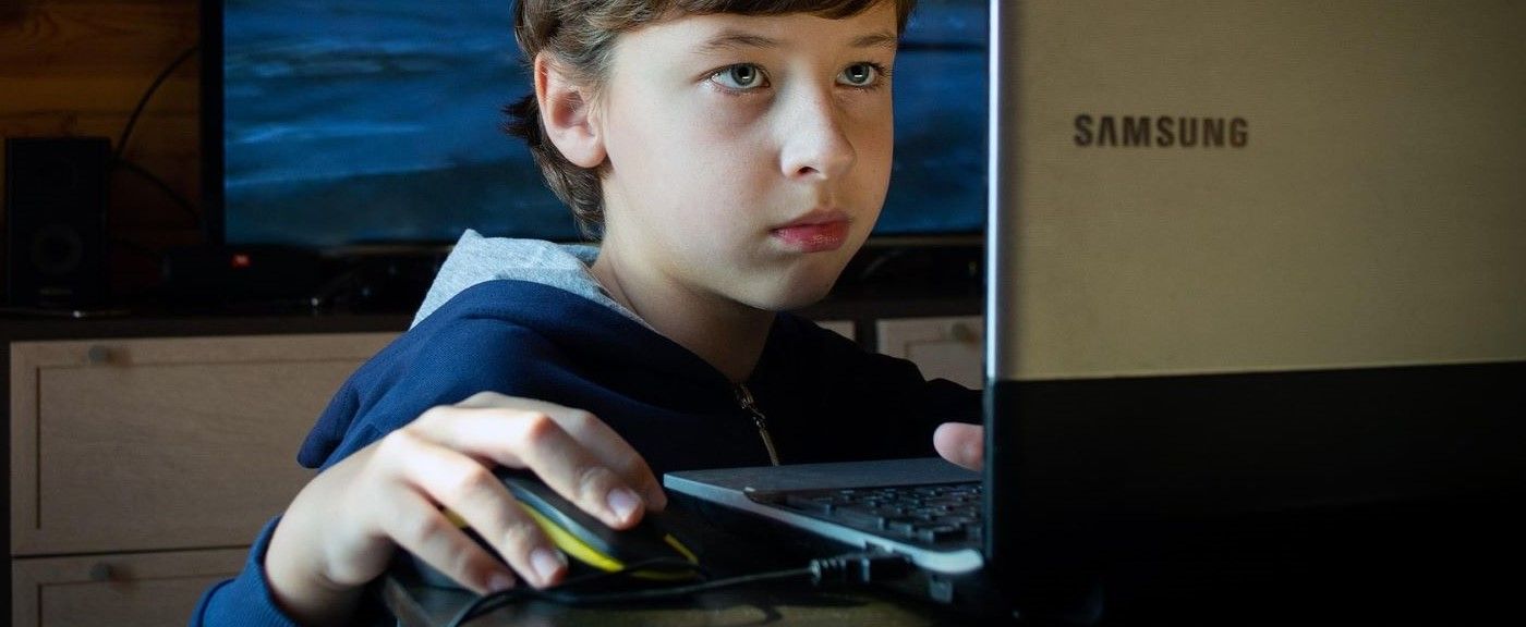 Niño pequeño utilizando un ordenador portátil en casa bajo supervisión, representando el uso temprano de la tecnología y la importancia de la protección digital infantil.